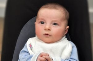 a baby looking up wearing a Bibby bib