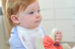 a baby holding a stuffed animal wearing a Bibby bib