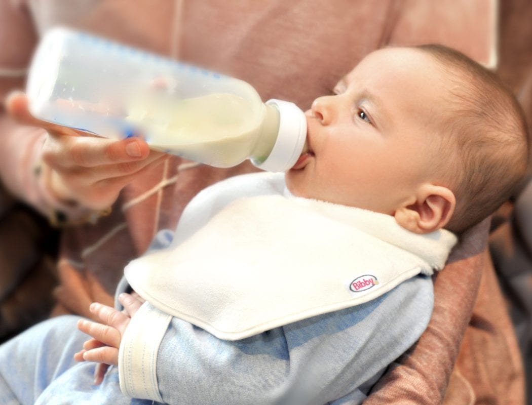 a baby drinking a bottle wearing a Bibby bib